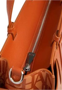Borsa arancione con interno in pelle liscia, zip argentata e dettagli con logo. Presenta un design minimalista con forma strutturata e texture morbida.