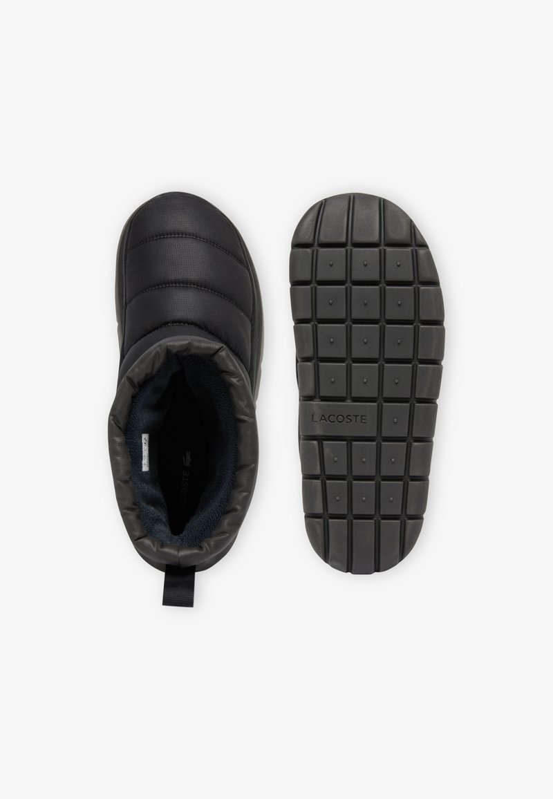 Schwarze Slipper-Stiefel mit gestepptem Obermaterial und weicher Auskleidung. Die Gummi-Außensohle weist ein Rippmuster und ein eingeprägtes Logo auf. Die weichen Materialien sorgen für Komfort.