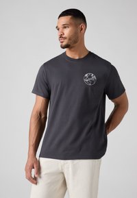 Sötétszürke pamut póló rövid ujjakkal és kerek nyakkal. A bal mellkason fehér földgömb mintával és "Levi's" felirattal.