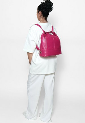 Fuchsia Leder-Rucksack mit doppelten Trägern und seitlichen Reißverschlüssen. Quadratische Form, mit glatter Oberfläche und subtilen Stichdetails.