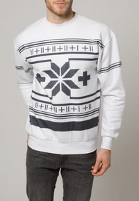 Bílá mikina s geometrickým černošedým vzorem, dlouhými rukávy, kulatým výstřihem a žebrovanými manžetami a spodním lemem.