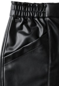 Pantaloni in finta pelle nera con vita arricciata, caratterizzati da cuciture a pannelli diagonali e un piccolo etichetta con il marchio vicino alla parte superiore. Texture liscia.