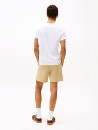 Weißes T-Shirt, beiges Shorts, braune Schuhe und weiße Socken. Einfaches Design, lässige Passform, mit sichtbaren Nähten und Taschen Details an den Shorts.