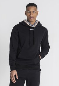 Svart hoodie med rutigt foder runt huvan, snörningsdetaljer och en framficka. Har ribbade ärmslut och fåll.