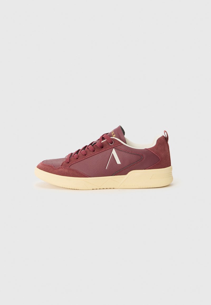 Maroon sneakers featuring textured leather and suede panels, cream rubber sole, and contrasting white logo on the side. Low-top design.