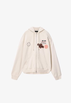Sweat à capuche zippé crème avec poches frontales, capuche ajustable par cordon et plusieurs écussons brodés, dont "ALLSAINTS" et des palmiers sur la poitrine.
