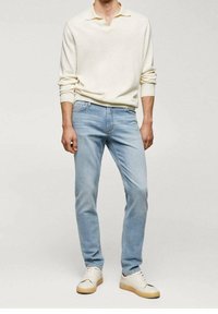 Vaaleansiniset suorat farkut, yhdistettynä kermanväriseen pitkähihainen poolopaitaan ja valkoisiin lenkkareihin, joissa on beiget pohjat.