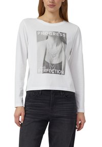 Biała t-shirt z długim rękawem z graficznym nadrukiem naszyjnika oraz tekstem "POSTĘP ponad DOSKONAŁOŚĆ", o skróconym, luźnym kroju.