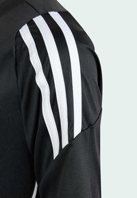 Svart träningsoberk med tre vita ränder på axeln, tillverkad av slätt material med en klassisk rundad halsringning.