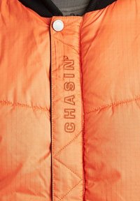 Felrood gewatteerd jack met zwarte kraag en "CHASIN" geborduurd in verticale richting langs de knopenlijst aan de voorkant.