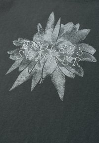 Graphique floral blanc avec le texte « ENDLESS SUMMER » en strass sur fond de tissu foncé.