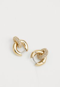 Boucles d'oreilles en ton or avec des designs de hoop entrelacés ; l'une ornée de strass clairs, surface lisse et finition polie.