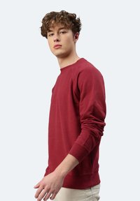 Felpa rossa in cotone con maniche lunghe e collo a giro. Presenta polsini e fondo a costine, design slim fit e dettaglio con zip laterale.