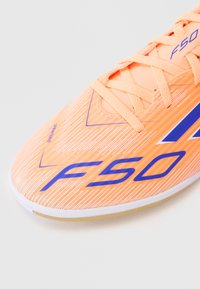 Oranži jalgpallikingad tekstiilse ülemise osaga, millel on sinised aktsendid ja "F50" bränding. Sidumisega disain, kerge tald, mis tagab vilkuse.