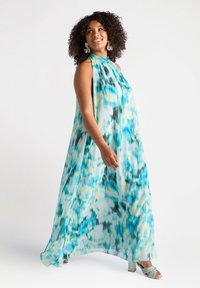 Rochie maxi dintr-un material ușor, fluid, cu un model abstract în nuanțe de turcoaz și galben, cu guler înalt și fără mâneci. Textură moale.