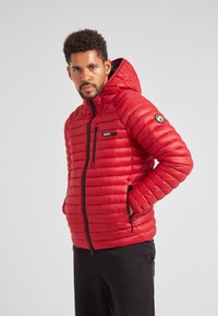 Giacca a vento rossa con cappuccio, caratterizzata da un design a righe orizzontali, zip nera e logo del marchio sul petto sinistro e sulla manica.