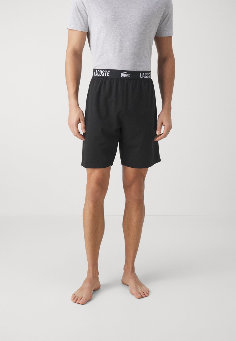 Shorts noirs avec ceinture élastique arborant le logo "LACOSTE", fabriqués en tissu doux et dotés d'une coupe décontractée.