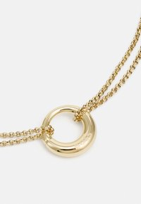 Collana dorata con ciondolo circolare recante la parola "BOSS". Le doppie catene con una texture attorcigliata arricchiscono il design.