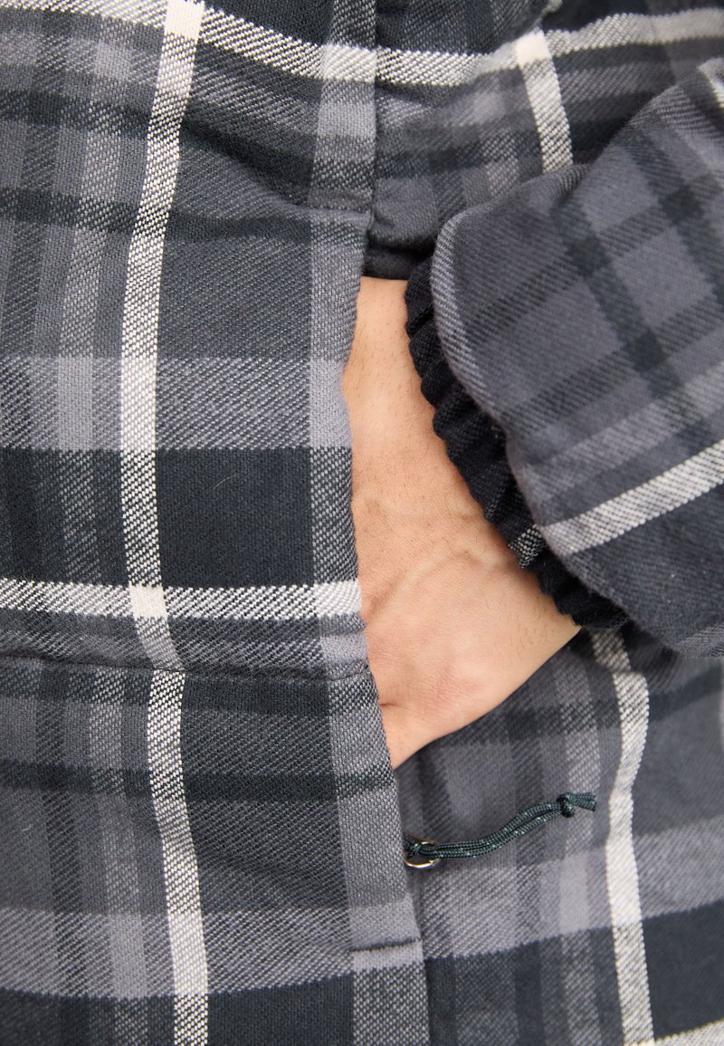 Szary i czarny kurtka w kratę z miękką teksturą, elastycznymi mankietami i bocznymi kieszeniami, z detalem ściągającym na dole.