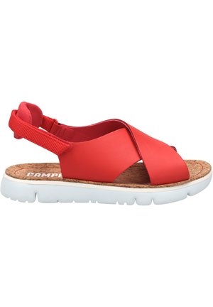 Red synthetic sandals with crossed straps, cork footbed, and white cushioned sole. Adjustable heel strap for secure fit.