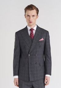 Dwurzędowy szary garnitur z subtelnym wzorem w kratkę, z wykładanymi klapami, dwoma guzikami oraz czerwoną krawatem w wzory i pasującą poszetką.
