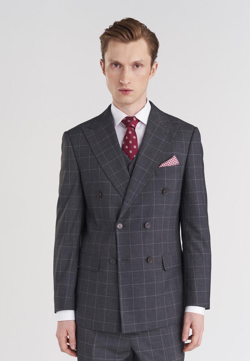 Dwurzędowy szary garnitur z subtelnym wzorem w kratkę, z wykładanymi klapami, dwoma guzikami oraz czerwoną krawatem w wzory i pasującą poszetką.