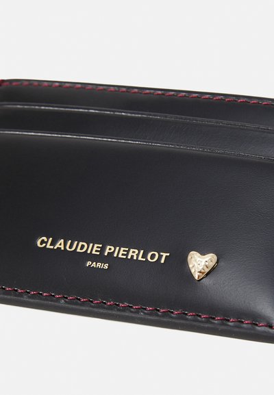 Il portacarte in pelle nera presenta un accento a forma di cuore dorato e cuciture rosse. "CLAUDIE PIERLOT PARIS" impresso in oro. Texture liscia.