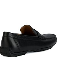 Mocassino in pelle nera con finitura liscia, punta arrotondata e cuciture decorative. Presenta una suola marchiata per una migliore aderenza e comfort.
