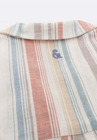 Tessuto con colletto e righe verticali in tonalità blu, rosso, beige e grigio attenuate, con un piccolo simbolo ampersand ricamato vicino al centro.