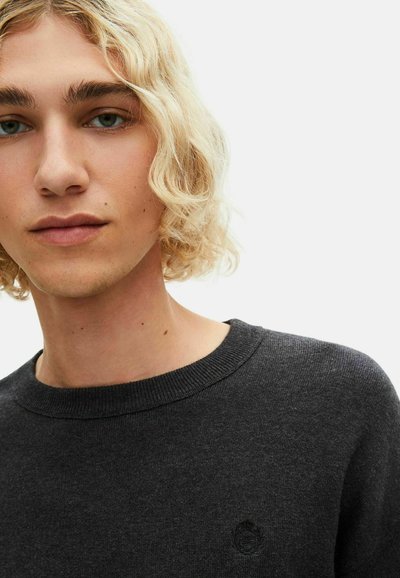 Maglione grigio carbone con scollatura rotonda e polsini a coste. Presenta un logo ricamato discreto nella zona sinistra del petto, realizzato in tessuto morbido.