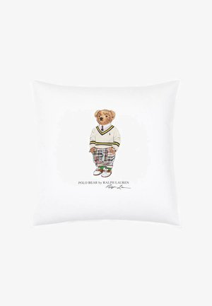 White cushion with a teddy bear illustration wearing a white sweater, plaid pants, and brown shoes, with "Polo Bear by Ralph Lauren" text below.