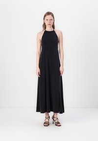 Must välja lõhiku ja pehme tekstuuriga must maksikleit, millel on voolav disain ja elegantne siluett. Kombineeritud rihmadega mustade kontsadega.