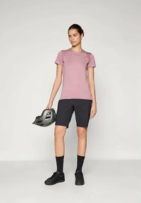 Šviesiai rožinė trumpomis rankovėmis palaidinė, juodos šortai, juodos kojinės ir batai. Laiko juodą dviratininkų šalmą. Paprastas, funkcionalus sportinis apranga.