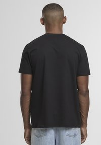 Schwarzes T-Shirt mit kurzen Ärmeln und Rundhalsausschnitt, aus Baumwolle, mit einem schlichten Design und einer lässigen Passform, von hinten betrachtet.