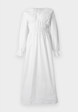 Μακρύ λευκό φόρεμα με μακριά μανίκια, σφηκωτή μέση και στήθος, μανσέτες με βολάν και λαιμόκοψη σε σχήμα V.