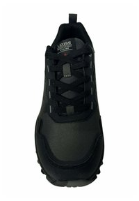 Zapatilla deportiva negra con parte superior de malla texturizada, cierre de cordones, cuello acolchado y una suela de goma gruesa con un patrón de tracción.