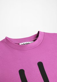 Roza bombažna majica s krožnim izrezom in velikim črnim grafičnim oblikovanjem spredaj, z gladko teksturo in kratkimi rokavi.