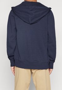 Felpa blu navy realizzata in morbido tessuto, caratterizzata da un grande cappuccio, maniche lunghe e polsini e orlo a costine. Design semplice senza motivi visibili.