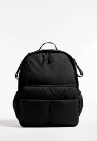 Black padded backpack with front zipper pocket, side pockets, top handle, and dual zipper closure on a plain white background.