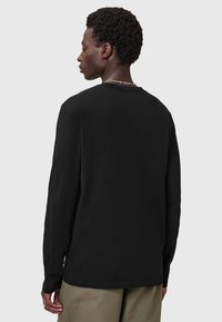 Schwarzes Langarmshirt aus weichem Baumwollmaterial. Verfügt über einen klassischen Rundhalsausschnitt und eine lockere Passform, mit einer Nahtdetail entlang des Saums.
