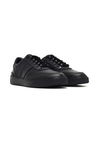 Baskets en cuir noir avec une texture lisse et un bout arrondi. Présente des lacets, une semelle en caoutchouc et des accents subtils sur les panneaux latéraux.