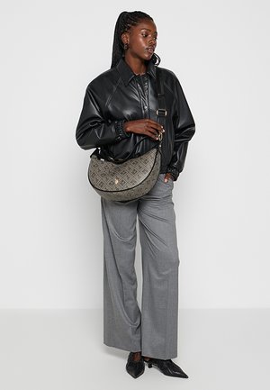 Czarna kurtka bomber z ekoskóry, szara, wzorzysta, duża torba, szare spodnie o szerokich nogawkach oraz czarne, szpiczaste buty, pozujące na neutralnym tle.