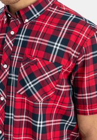 Červená, černá a bílá kostkovaná košile s krátkým rukávem a knoflíkovým zapínáním, s přední kapsou na hrudi a vyšívaným logem "Lonsdale London".