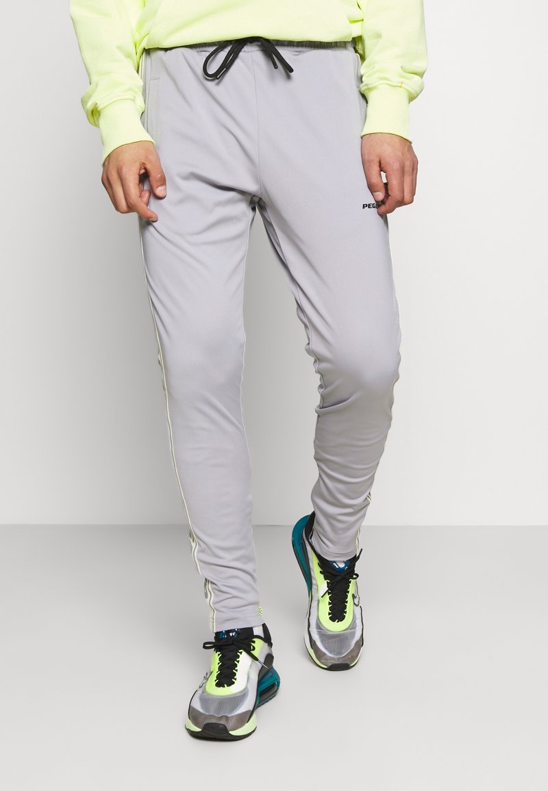 Ljusgråa träningsbyxor med dragsko i midjan, sidostripes och en åtsittande design, i kombination med färgglada löparskor med nätinslag.