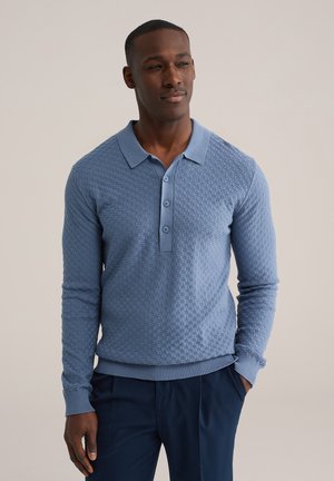 Lichtblauw poloshirt met lange mouwen, een gestructureerd patroon, een drieknopsbies en geribbelde manchetten. Draagt men met marineblauwe broek, elegante pasvorm.