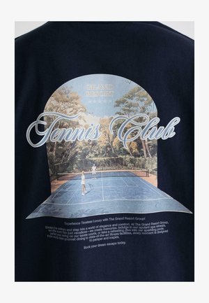 Sötétkék póló, grafikus nyomattal, ami egy teniszpályát ábrázol, két játékossal, fákkal körülvéve, és a "Tennis Club" felirattal.