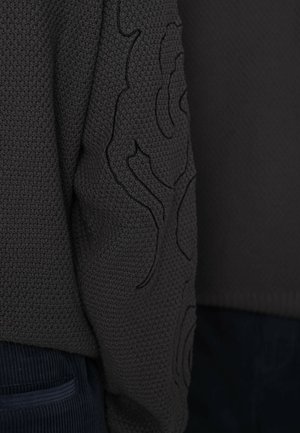 Maglione grigio scuro lavorato a maglia con superficie testurizzata e motivo ricamato sulla manica. Orlo arrotondato e polsini a coste.