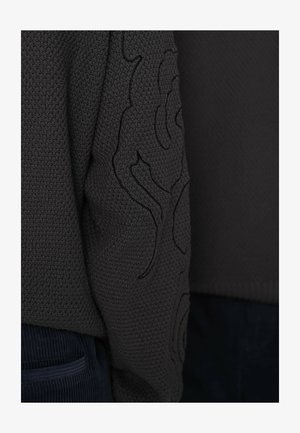 Pull gris foncé en maille avec surface texturée et motif brodé sur la manche. Ourlet arrondi et poignets côtelés.