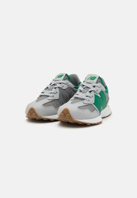 Las zapatillas deportivas grises y verdes presentan una parte superior texturizada, puntera redonda, cierre con cordones y una suela de goma con patrones de relieve visibles.