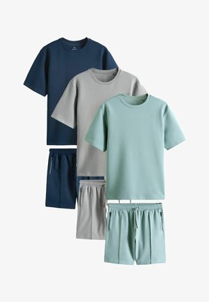 Drei Sets aus einfarbigen Freizeit-T-Shirts und passenden Shorts in Marineblau, Hellgrau und Hellteal mit Reißverschlusstaschen.